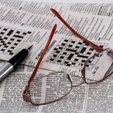 Crossword puzzle with glasses and pen lying on top