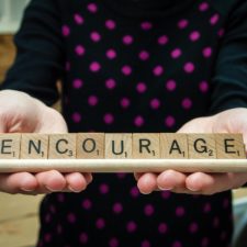 Scrabble tiles on a rack spelling out 'encourage'