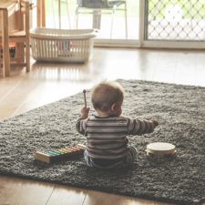 Toddler on a mat with a xylophone and tambourine