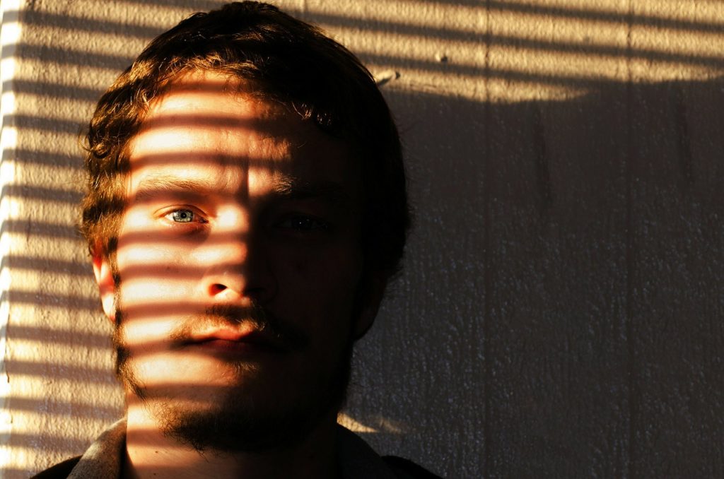 Man crying, shutter shadows across his face