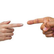 Woman and man's hands, pointing fingers at each other as if in argument