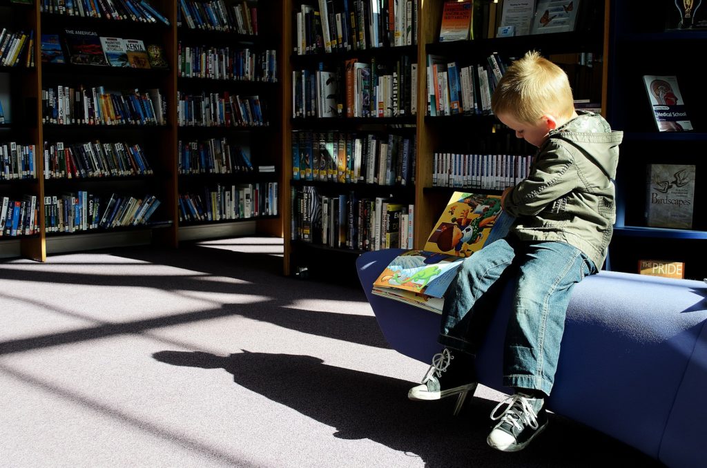 Child sitting reading a picture book in a library