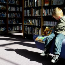Child sitting reading a picture book in a library