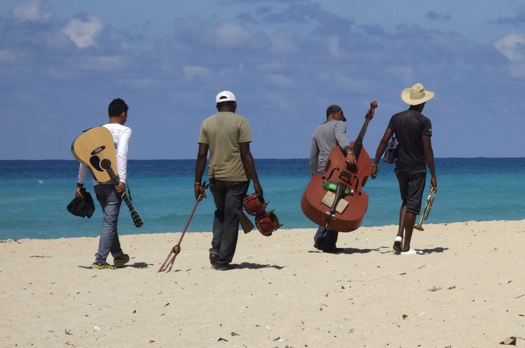 Four musicians walking away on a beach