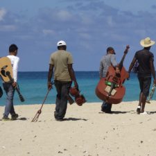 Four musicians walking away on a beach
