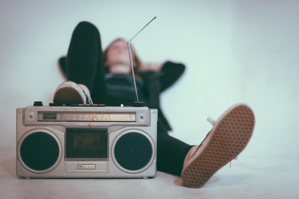 Person lying back with their foot on an old radio player, listening