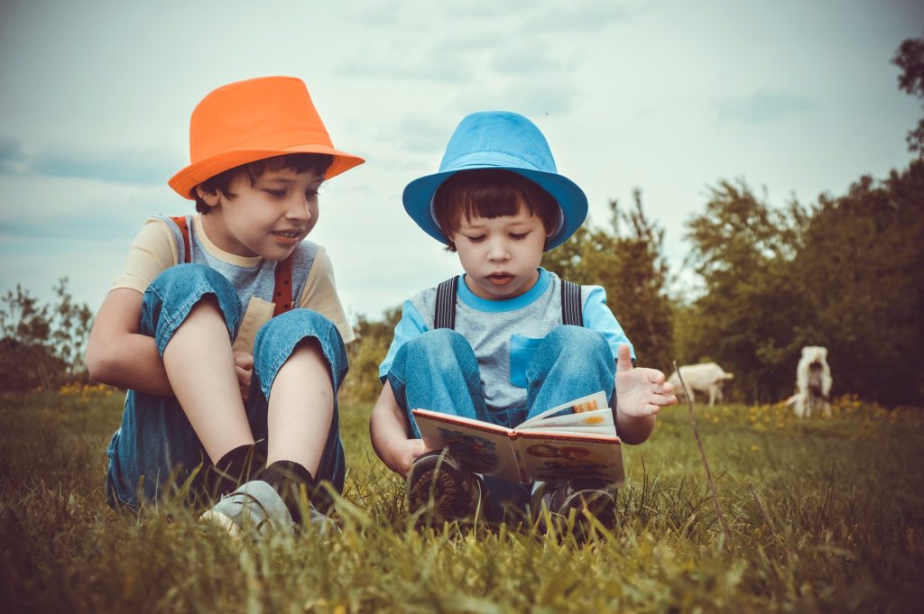 Two young boys reading and discussing a book