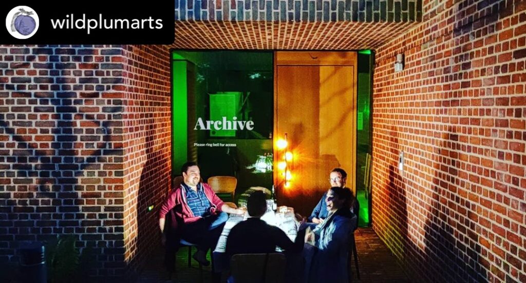 Composers sitting at a table outside the Red House Archive building